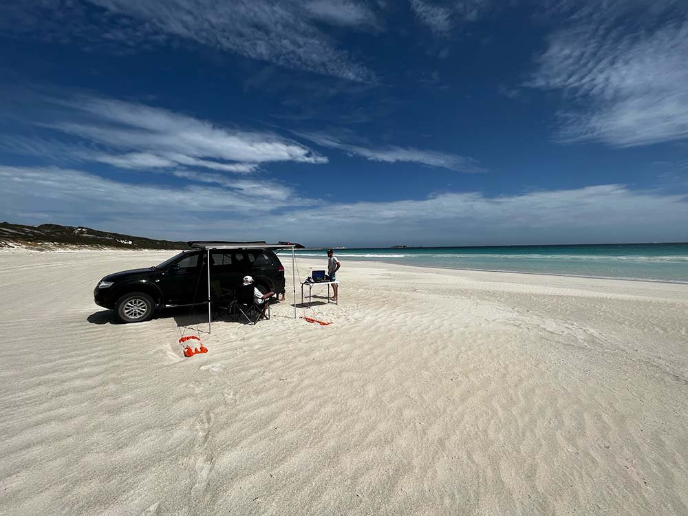 Boranup Beach with black 4WD and explorer in front of white sands and turquoise ocean.