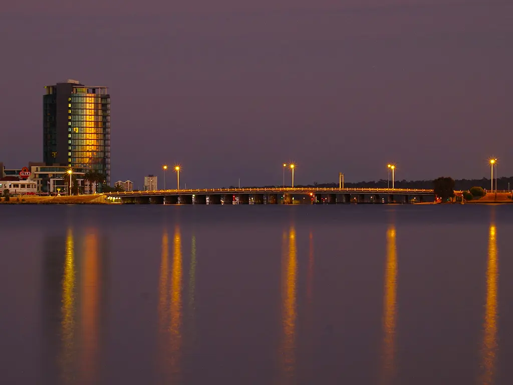 Canning Highway Bridge in Como, Perth WA at dusk with fishers on either side of the fishing platform on the riverfront.