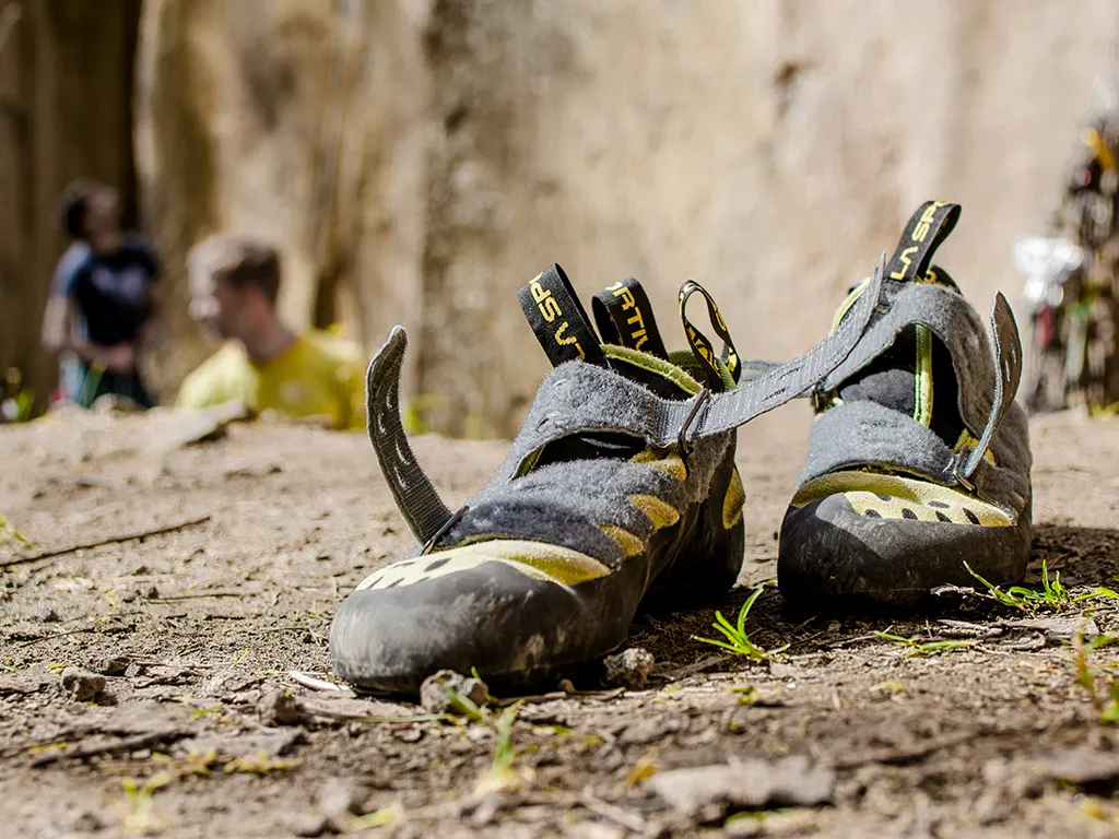 Pair of dirty outdoor bouldering shoes in Perth with crag out of focus in background.
