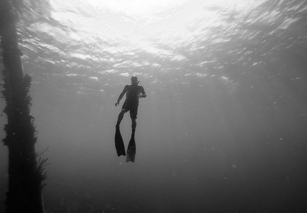 Greyscale image of freediver returning to ocean's surface, practicing mammalian dive response