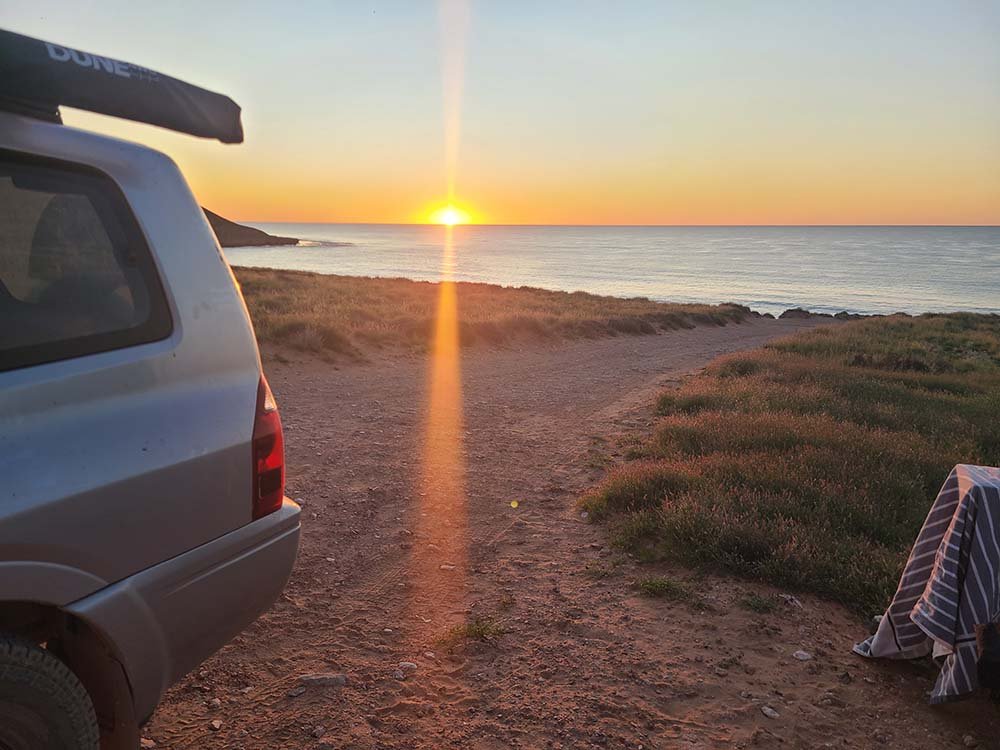 Rear of 4WD at Red Bluff campground with sunsetting over horizon in the background in the horse shoe bay