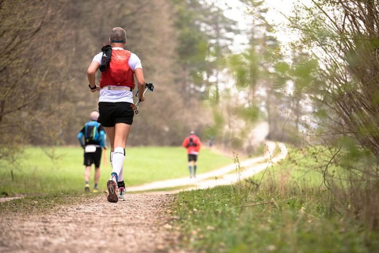 Trail runners in running gear running on dirt trail in forrest
