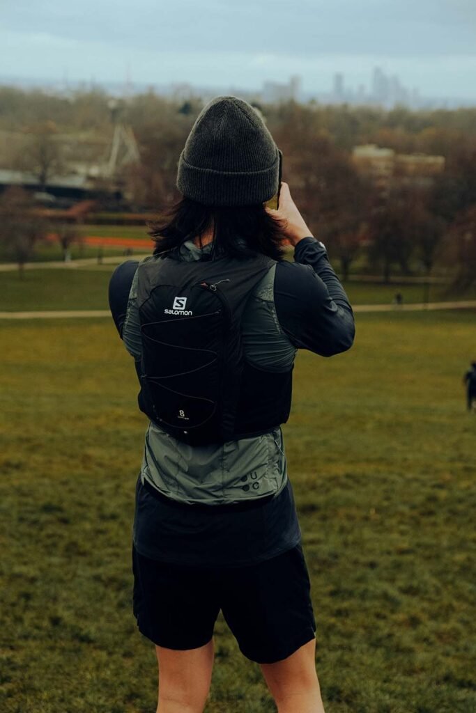 Trail runner taking photo of valley with trail running vest