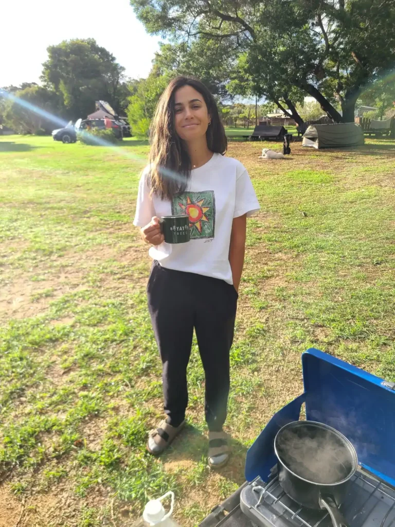 Female hiker with coffee in grassy campground at Fair Harvest in Margaret River, West Australia.