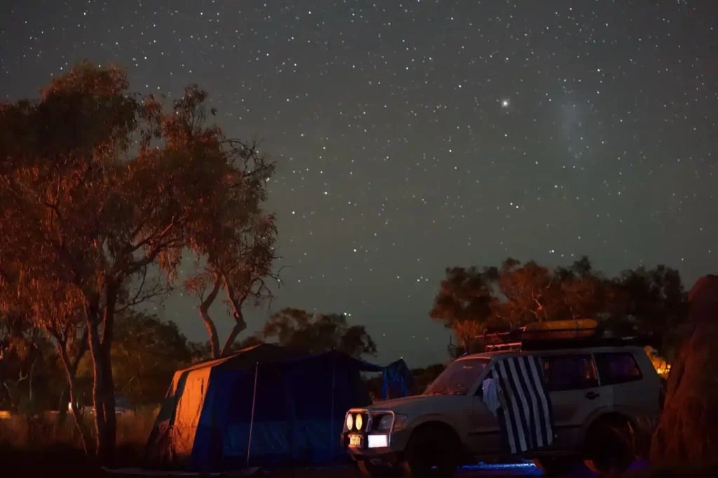 Campsite at Eco Retreat Campground in Karijini National Park at nighttime, a four wheel drive and tent under a sky full of stars.