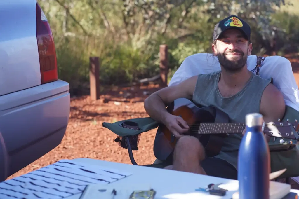 Camper playing guitar at campsite at Dales Campground, Karijini (near Mount Bruce).
