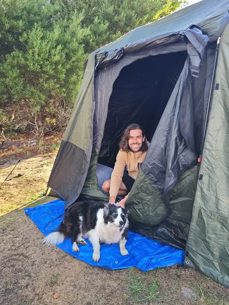 Dog and camper at the entrance of tent at Fair Harvest retreat and campground in Margaret River, WA.