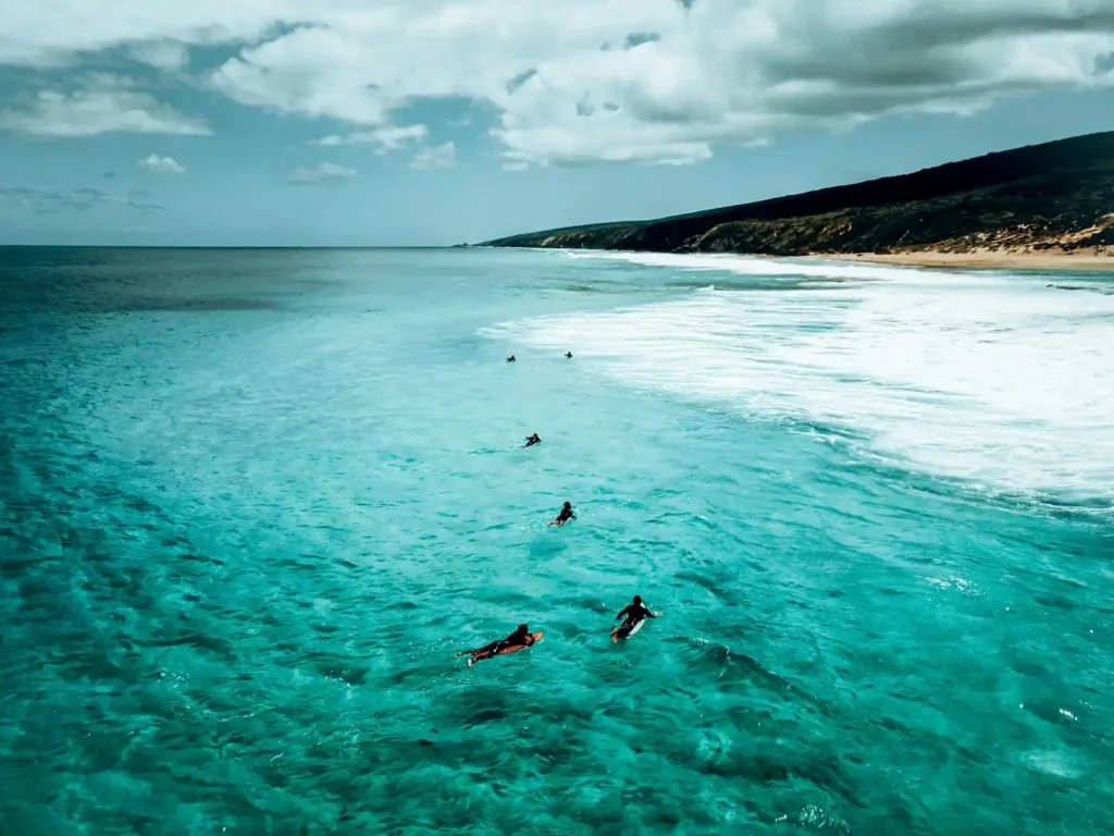 Turqoise waters with surfers on surface of ocean in southwest West Australia, Margaret River.