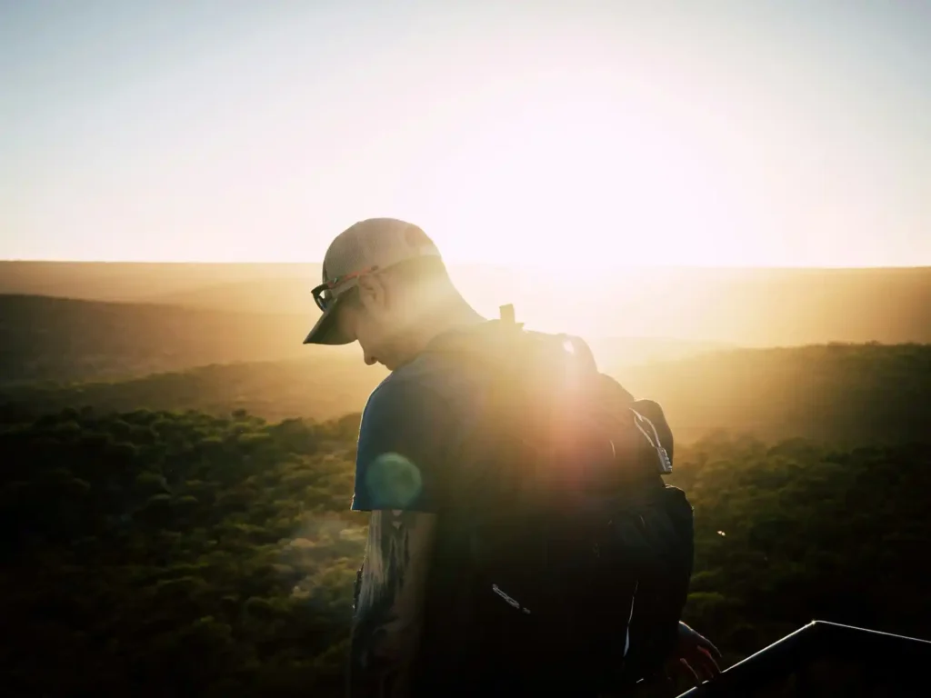 Silhouette of hiker looking down on tough hiking trail in Perth, West Australia with sunset in background.